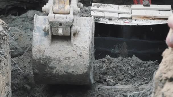 Cubo de excavadora alisando la arena del suelo y la suciedad en el sitio de construcción. Lento. — Vídeo de stock