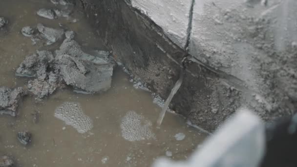 Špinavá voda vylévá přes mezeru v betonu do louže. — Stock video