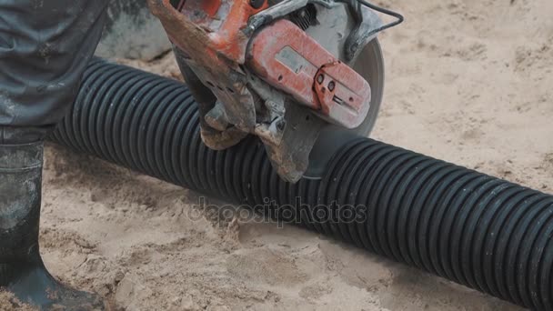 Warker scie côtelée tuyau en plastique avec scie circulaire sur la surface du sable, ralenti — Video