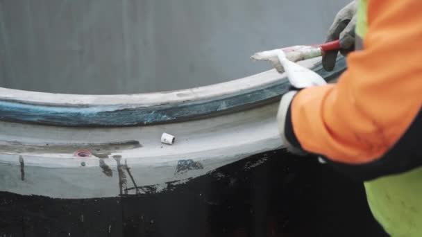 Travailleur mettre de la colle blanche sur le bord de l'anneau de trou d'homme en béton avec brosse. Mouvement lent — Video