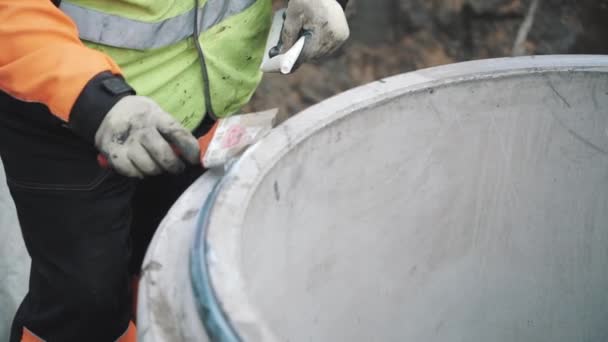 Builder colocar cola branca na borda do anel bueiro de concreto com escova. Movimento lento — Vídeo de Stock