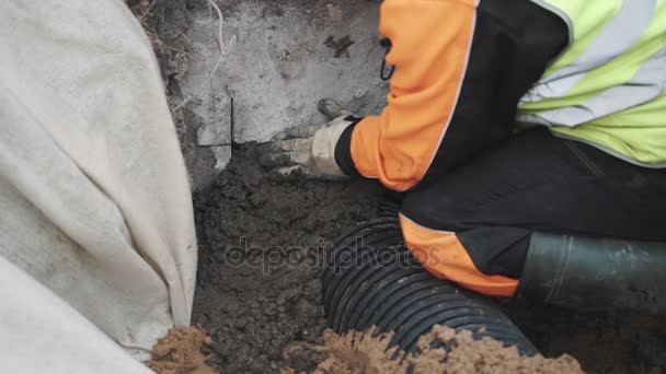 Builder seal stitch ribbed plastic pipe and concrete hole with cement — Stock Video