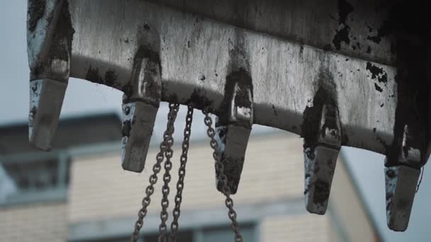 Dreckige Baggerlöffel aus Metall mit angebrachten Ketten auf Baustelle — Stockvideo