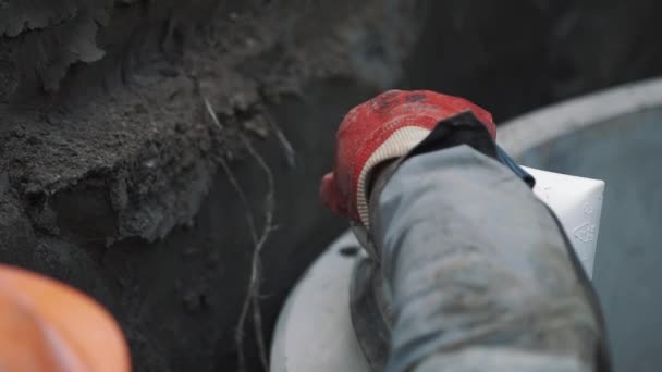 Il costruttore in cappello rigido applica la colla intorno al bordo dell'anello del tombino della camera di cemento — Video Stock