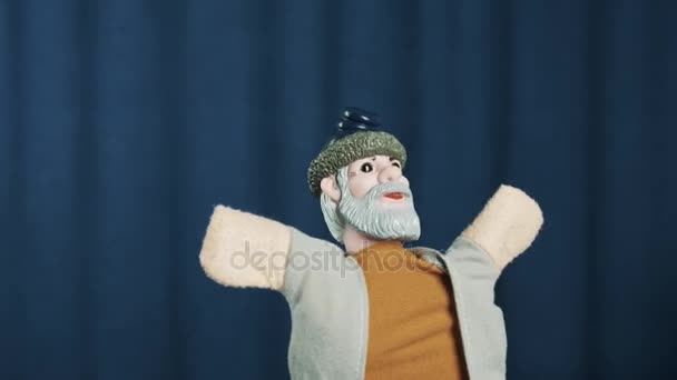 Крестьянская кукла, кажется, приветствует публику руки широко распространенные на голубом фоне — стоковое видео