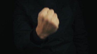 Uzun kollu ceketli, yumruk çekerek erkek eli yapmak hareket oturum threating