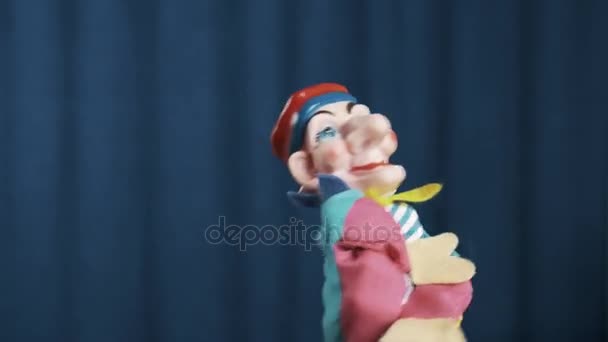 Блазень рука ляльковий з'являється на сцені з синьому фоні, привітання аудиторії — стокове відео