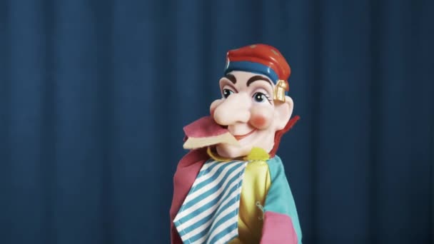 小丑手偶握手，并把它放到嘴里，点头对蓝色背景 — 图库视频影像