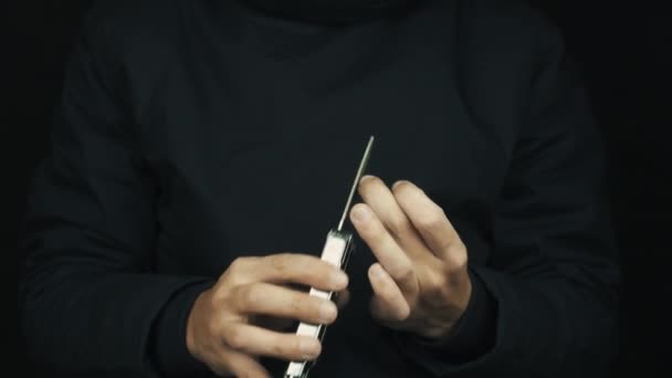 Male hands in long sleeve jacket using multitool file to trim nails — Stock Video
