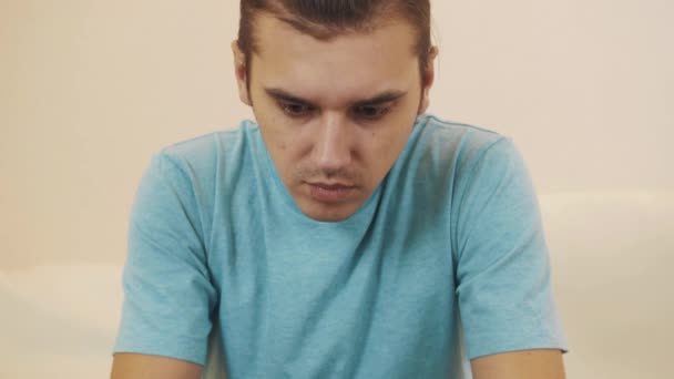 Engrossado homem de camisa azul sentado no sofá jogando videogame em comprimido revestido — Vídeo de Stock