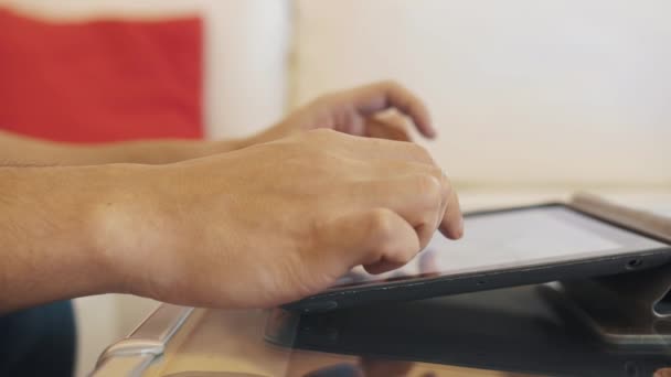 Comprimé Cased sur un bureau en verre utilisé par le gars en chemise bleue avec un noeud de cheveux, parlant 