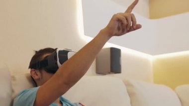 Sanal gerçeklik kulaklık deneyim açıklayan kanepede oturan neşeli adam