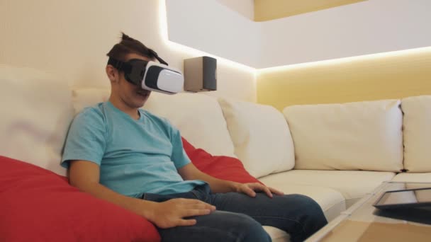 Naughty man sitting on sofa in virtual reality headset watch lewd pornographic video — Stock Video