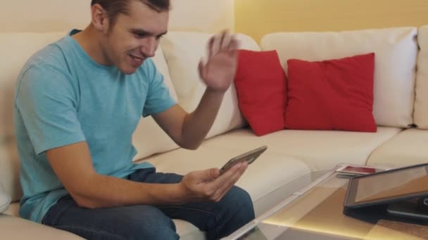 Χαρούμενη man ξεκινά ζωντανά βίντεο από το smartphone, την εμφάνιση του σαλόνι, συνομιλίες — Αρχείο Βίντεο