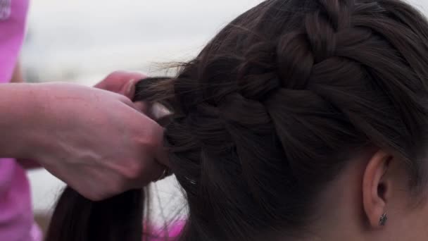 Woman in pink shirt weaving braid to young brunette girl. Hairstyle. Fashion — Stock Video