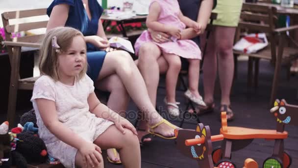 Matek i dzieci siedzieć na tarasie restauracji. Letnie imprezy. Dokonywanie fryzurę — Wideo stockowe