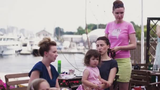 Ragazza in camicia rosa intrecciare treccia alla giovane donna con bambina in ginocchio. Terrazza — Video Stock