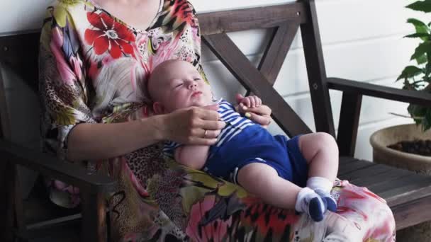 Mother with sleepy baby boy sit on terrace of restaurant on celebration event. — Stock Video