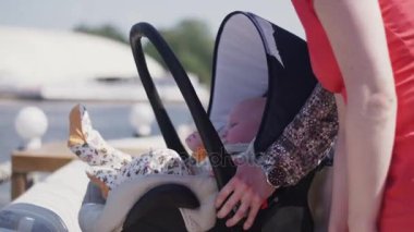 Anne bebek arabası şirin bebek çocukla sokakta kal. Aile. Yaz