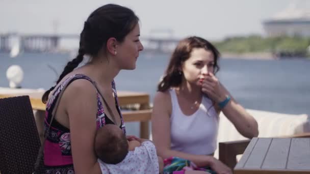 Mamma håller på händer baby på terrassen vid havet talar med tjej. Vänner. Vatten — Stockvideo