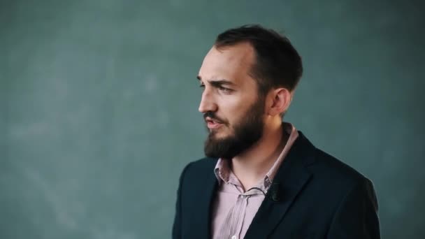Homem barbudo de casaco e camisa listrada fala com confiança sobre fundo isolado — Vídeo de Stock