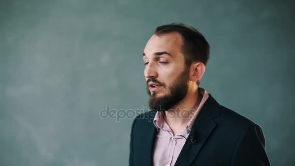 Barbudo hombre con chaqueta y camisa a rayas dando entrevista sobre fondo aislado — Vídeos de Stock