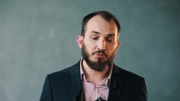 Barbudo hombre con chaqueta y camisa a rayas habla con confianza la celebración de la plataforma de la cámara — Vídeos de Stock