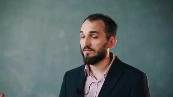 Бородатый мужчина в куртке и полосатой рубашке отвечает на вопрос шуткой и смехом — стоковое видео
