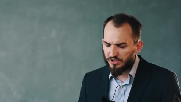 Barbudo hombre con chaqueta y camisa a rayas comparte opinión sosteniendo videocámara — Vídeo de stock