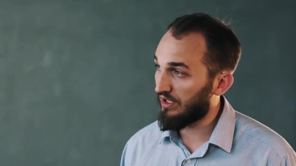 Молодой бородатый бизнесмен в полосатой рубашке объясняет что-то страстно — стоковое видео