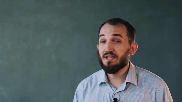 Joven hombre de negocios barbudo con camisa a rayas habla apasionadamente en la pared aislada — Vídeo de stock