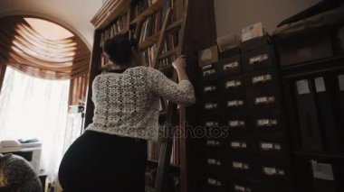 Merdiven alarak kitap kitaplık eski stil kitaplığı iç üzerinden tırmanma kadın