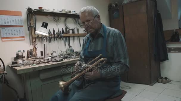 Dolly skott master i glasögon arbete med mässing tuba och instrument i verkstad — Stockvideo