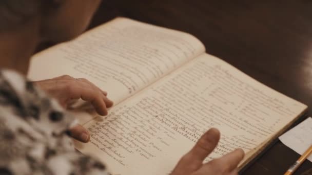 Close up shot of old woman hands leaf through book russian cursive text on table — Stock Video