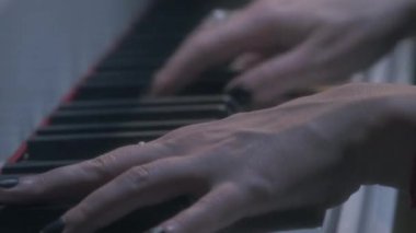 Yüzük, siyah oje ve kırmızı string bilezik piyano ile kadın kolları