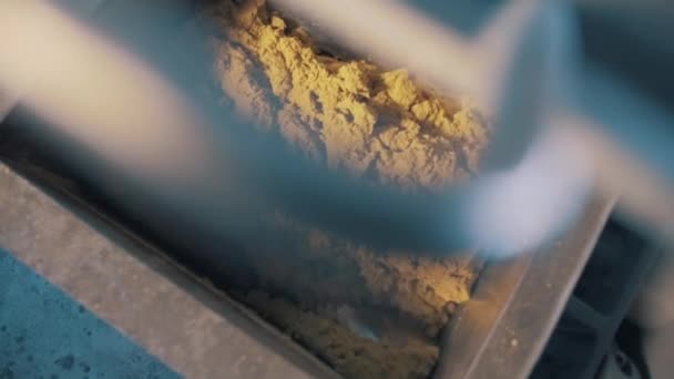 Spinning blades inside industrial machine mixing yellow kinetic sand mass — Stock Video