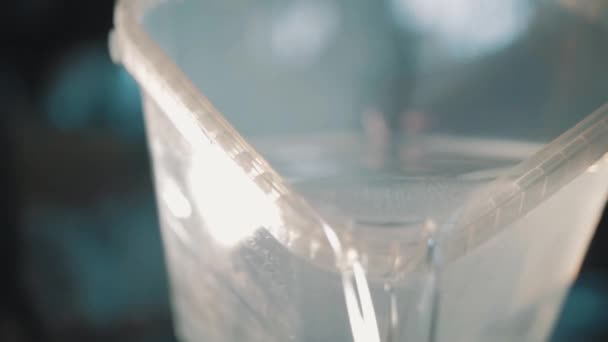 Eau claire versant lentement un récipient en plastique transparent carré 