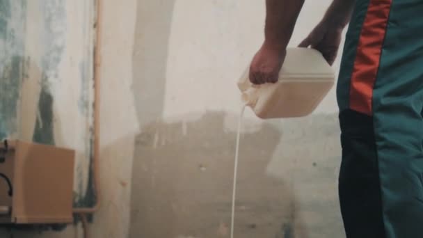 Człowiek w pracy spodnie wycieki biały polerowanie płynu na nowy parkiet — Wideo stockowe