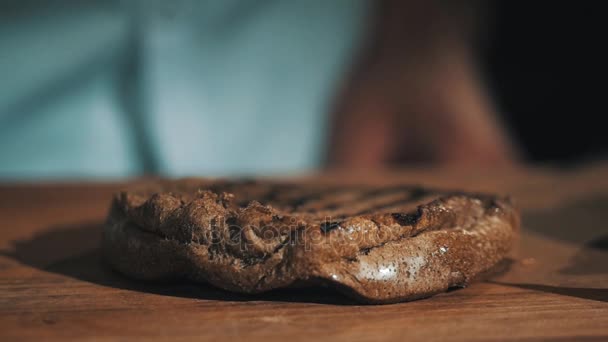 Chefe de cozinha em roupão branco derrama ketchup em pão grelhado na mesa de madeira — Vídeo de Stock