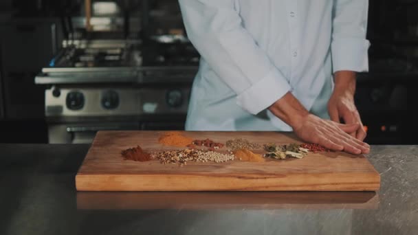 在白色长袍的男性烹饪首席抛掉木菜板香料 — 图库视频影像