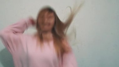 Genç kız mutlu beyaz duvar önünde sallayarak saç atlama heyecanlı