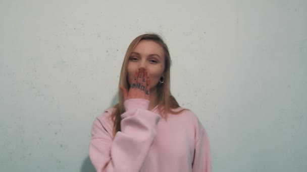 Ελκυστική νεαρή γυναίκα σε ροζ φούτερ χαμογελώντας και έστειλε αέρα φιλί στην κάμερα — Αρχείο Βίντεο