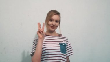 Beyaz duvar önünde üç parmak Yüksel genç ve güzel sarışın kadın