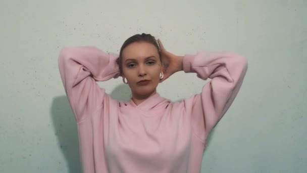 Attractive young woman with flesh tunnels in pink sweatshirt making hair tail — Stock Video