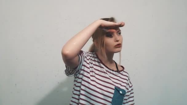 Chica rubia bonita en camisa a rayas, poner la mano sobre los ojos y mirar a su alrededor — Vídeos de Stock
