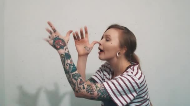 Menina loira engraçada no bullying camisa listrada, agitar os dedos e mostrar split tounge — Vídeo de Stock