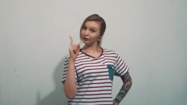 Attractive young tattoed woman in striped shirt, have idea and pull up finger — Stock Video