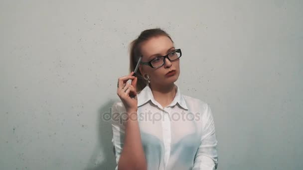 Mujer aburrida en camisa blanca, con expansores de orejas gira pluma contra cabeza — Vídeo de stock