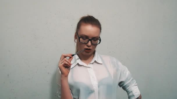 Eftertänksam kvinna i vit skjorta, med örat köttet tunnlar biter på pennan, tänkande — Stockvideo