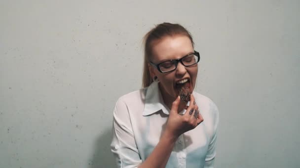 Aggressiv kvinna i vit skjorta, med örat kött tunnlar biter på granitsten — Stockvideo